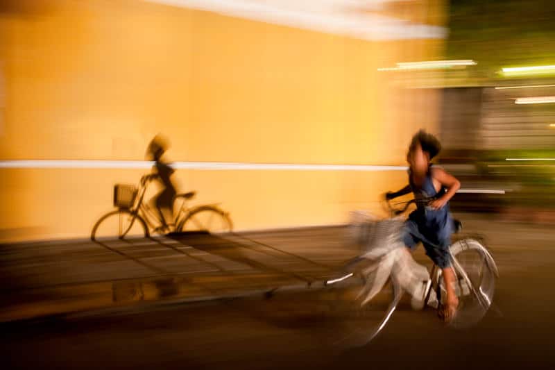 Young boy and his shadow cycle through Hoi An at night