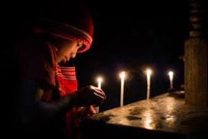 Novice monk in Myanmar lighting candles at night