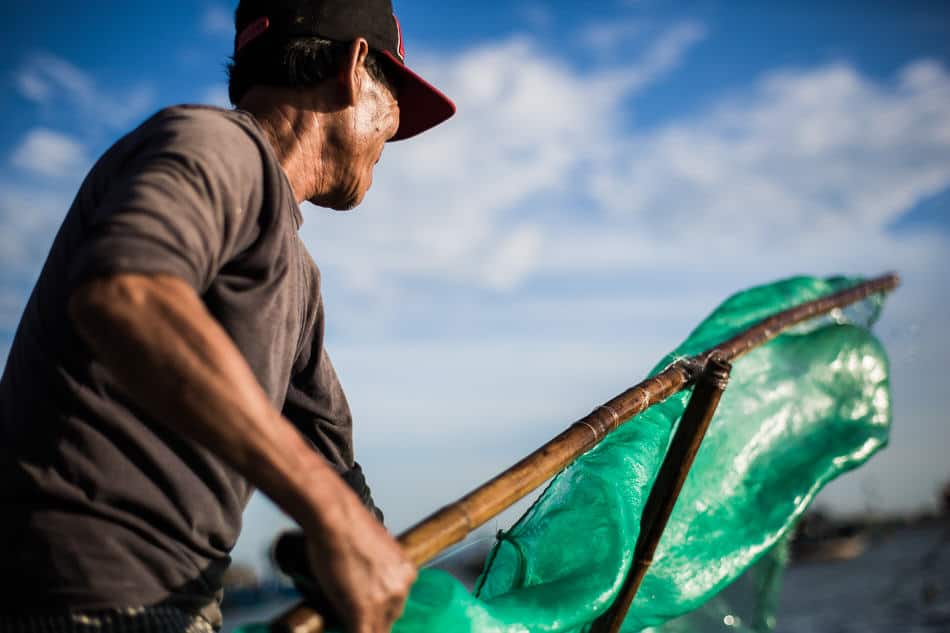 Vietnamese fisherman cleaning his net