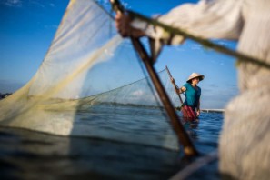 A large net is dragged through the water by a pair of fishermen in Vietnam
