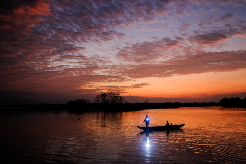 man in Vietnam on a small wooden boat with a light on the river near Hoi An