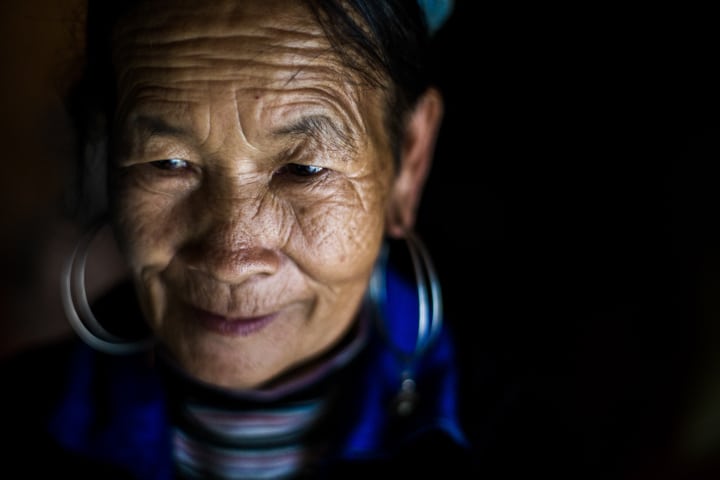 An Up-close portrait of a Hmong woman on a black background in North Vietnam - Pics Of Asia Photos Travels Tours