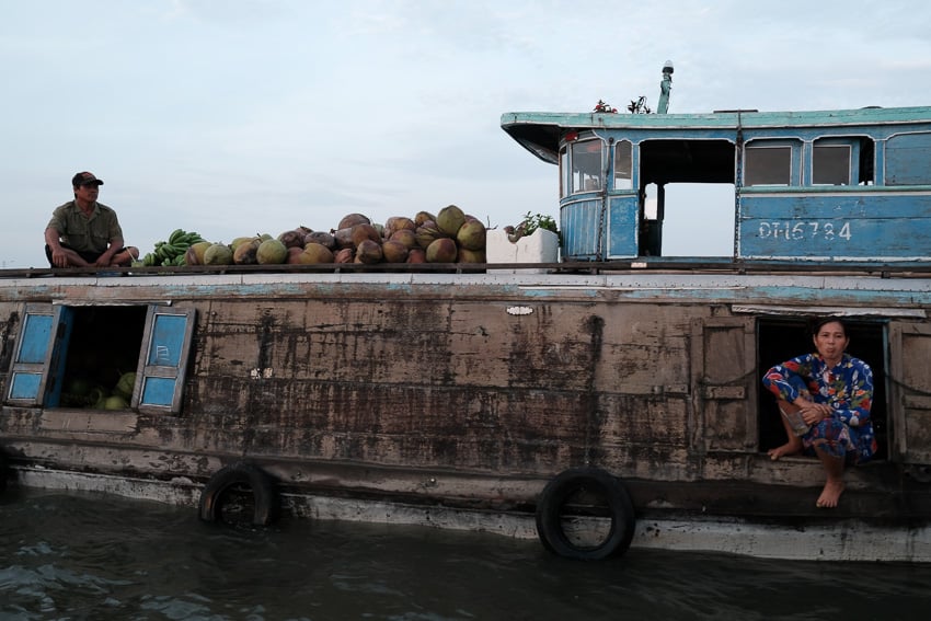 couple selling coconuts on their boat in the Mekong delta