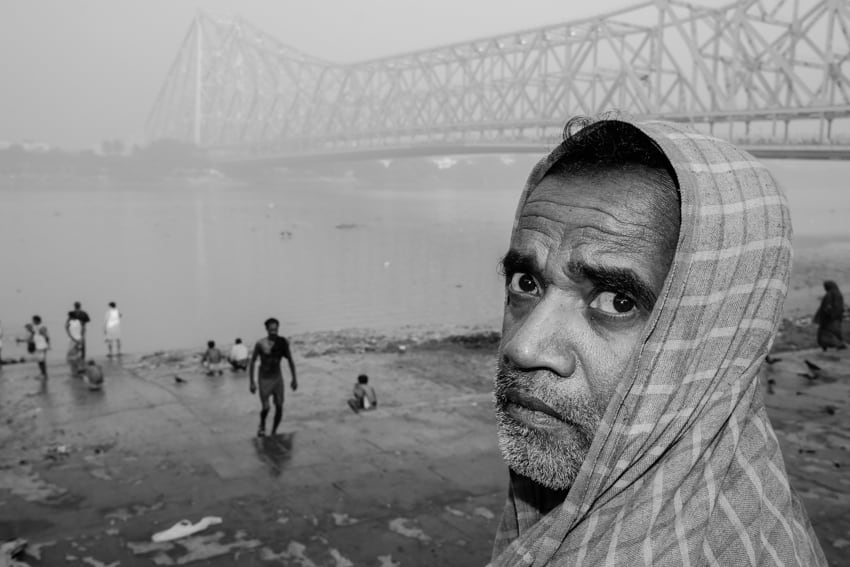 A man stares at the camera in front of the Howrah bridge, Kolkata