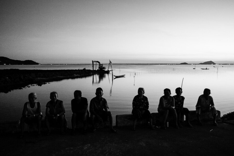 a group of elderly people sitting on the side of the road in central Vietnam 