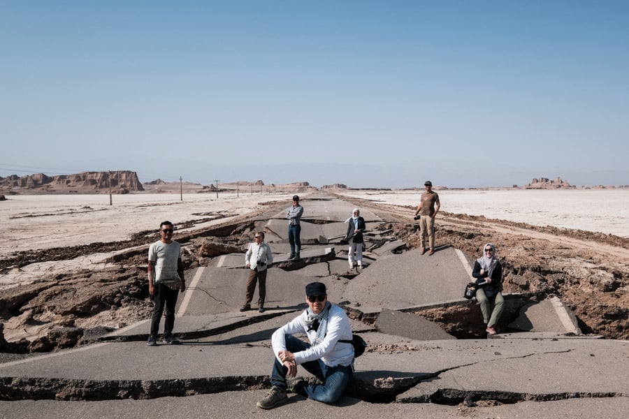 The photography tour group from pics of asia in iran poses in front of a broken road