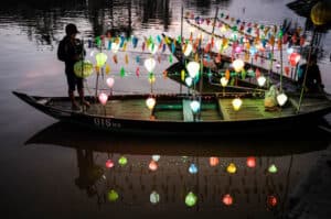 A man sets up the lanterns on his boat at sunset in Hoi An old town
