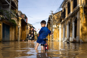 a boy and his bicycle in the flooded streets of hoi an old town after the Noru typhoon