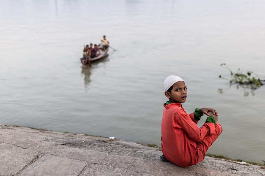 A boy sitting along the river in Barisal city