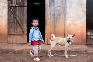 A Koho girl walks next to a dog in a village in central Vietnam