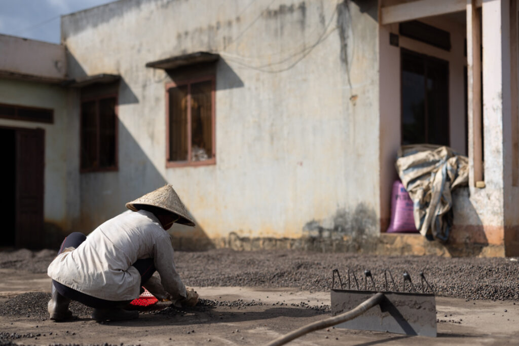 Koho woman drying coffee in front of her house in Dalat