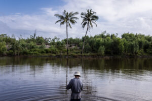 a man fishes in the river with coconut trees in the background in Vietnam