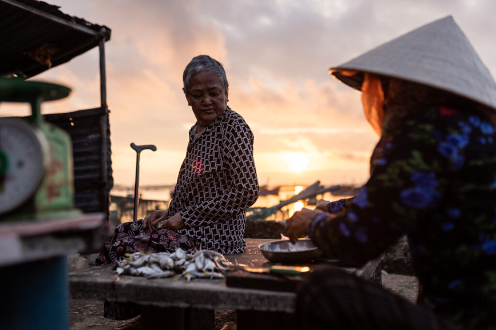 A woman is buying fish at sunrise in a fish market in Song Cau, Vietnam.