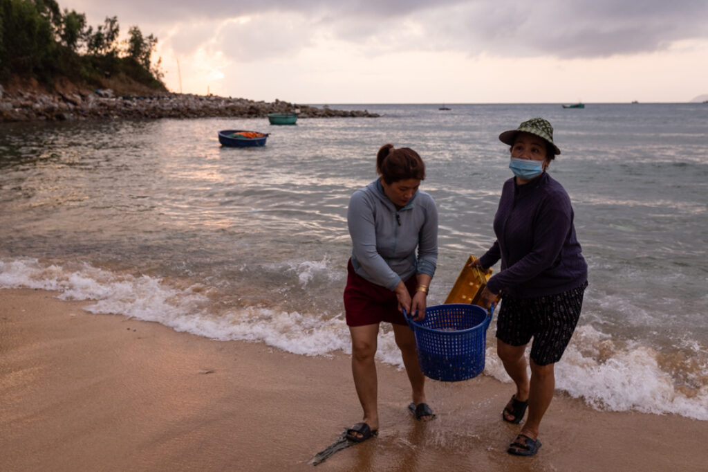 two women bring fish from the sea on a beach in Vietnam