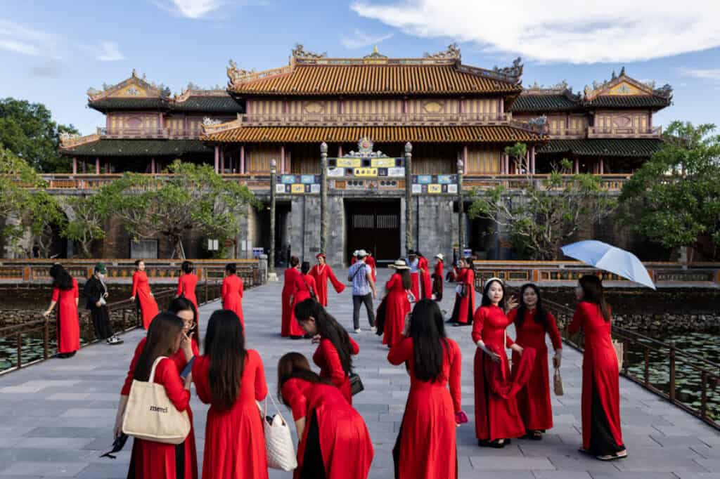 a group of women in red Ao Dai visit Hue citadel in Vietnam